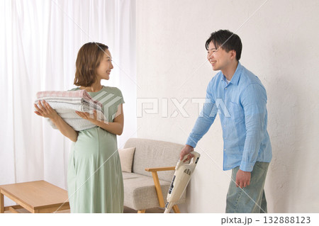 妊婦の女性と楽しそうに話しながら掃除機をかける若い男性 132888123