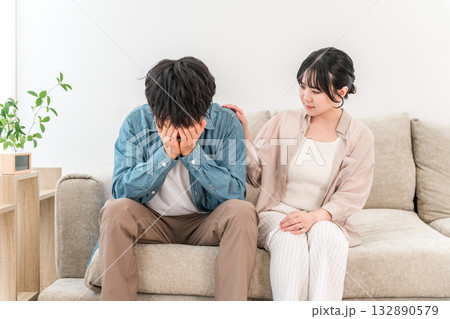 ソファーで落ち込む男性を慰める女性,夫婦,カップル ソファーで落ち込む男性を慰める女性,夫婦,カップル 132890579