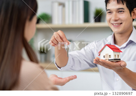 Real Estate Transaction. Agent handing over keys and house model to a client. 132890697