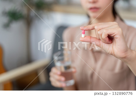 Medication Management. Woman preparing to take a capsule with a glass of water. 132890776