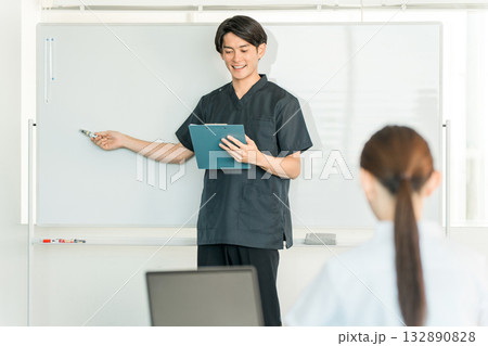 医療カンファレンスなどでホワイトボードの前で説明する医師,看護師,薬剤師の男性スタッフ 医療カンファレンスなどでホワイトボードの前で説明する医師,看護師,薬剤師の男性スタッフ 132890828