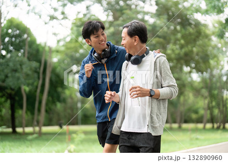 Father and Son Wellness Journey. Active bonding through exercise in a green park. 132890960