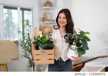 Moving Home. Woman carrying plants and box during relocation. Moving Home. Woman carrying plants and box during relocation. 132890972