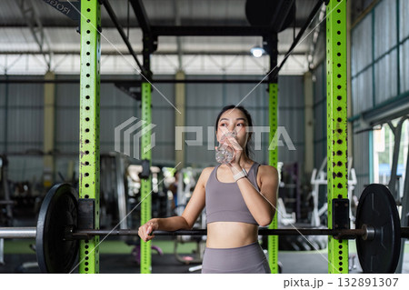 Hydration Focus. Client taking a water break during workout in gym. Hydration Focus. Client taking a water break during workout in gym. 132891307