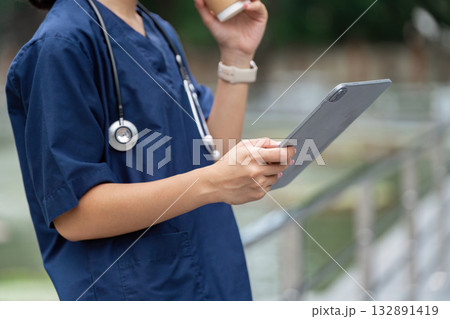 Healthcare Professional. Nurse holding tablet and coffee, preparing for patient care. Healthcare Professional. Nurse holding tablet and coffee, preparing for patient care. 132891419
