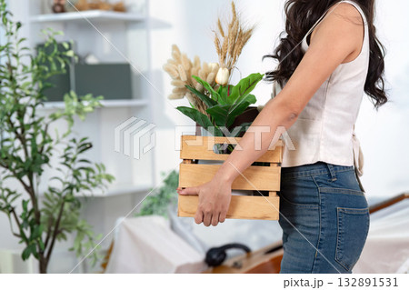 Moving Home with Plants. A woman carries a wooden crate filled with decorative plants. Moving Home with Plants. A woman carries a wooden crate filled with decorative plants. 132891531
