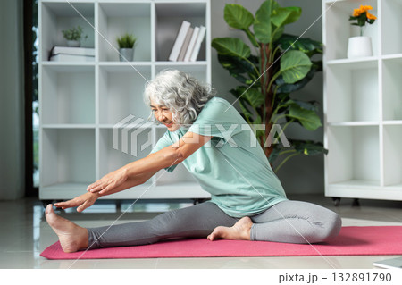 Senior Fitness and Flexibility. Elderly woman stretching on yoga mat indoors. 132891790