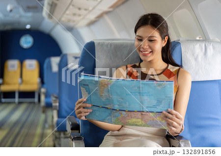 Travel Planning. Young woman reading map on airplane for her next destination. Travel Planning. Young woman reading map on airplane for her next destination. 132891856