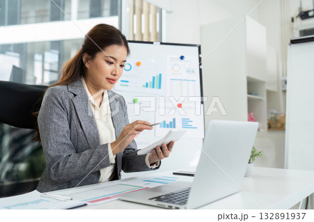 Remote Work and Productivity. Businesswoman analyzing data on tablet in modern office. Remote Work and Productivity. Businesswoman analyzing data on tablet in modern office. 132891937