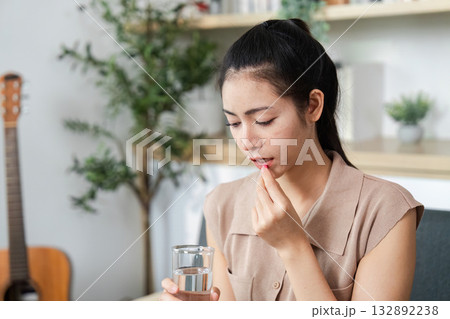 Mental Health and Wellness. Young woman taking medication with water for emotional resilience. 132892238