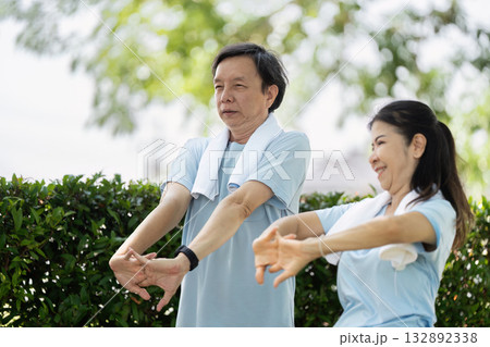 Wellness and Senior Fitness. An elderly couple engaging in stretching exercises outdoors to promote health and well-being. Wellness and Senior Fitness. An elderly couple engaging in stretching exercises outdoors to promote health and well-being. 132892338