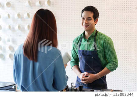 Sustainability and Coffee Culture. A barista engaging with a customer in an eco-friendly cafe. Sustainability and Coffee Culture. A barista engaging with a customer in an eco-friendly cafe. 132892344