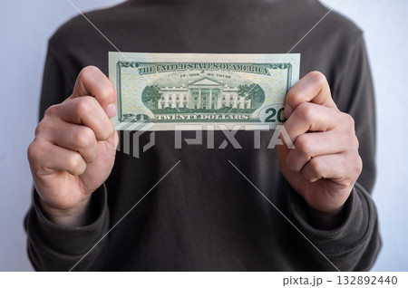 Cropped shot view of woman holding and showing twenty American dollar banknotes in hands. The US Dollar is the currency of United States. 132892440