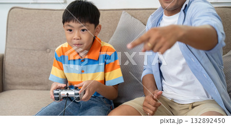 Family Bonding through Gaming. A young boy playing video games with his father at home. 132892450