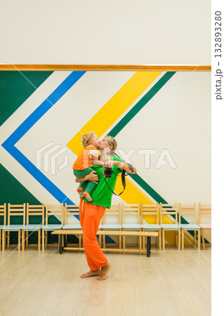 A man is holding a child in his arms and the child is wearing a green shirt 132893280