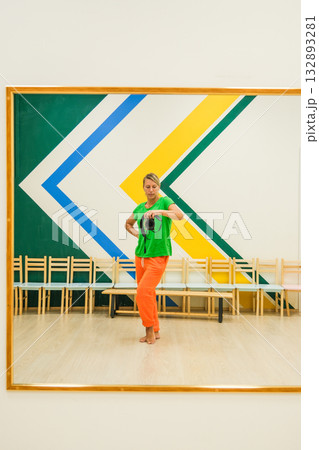 A woman in a green shirt is standing in front of a mirror 132893281