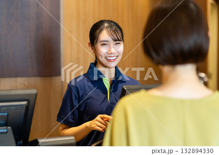 ジムで受付をする若い女性のスタッフ　撮影協力：スポーツクラブ&サウナスパ ルネサンス 幕張24 132894330