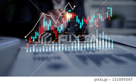 Businessman Analyzing Financial Data and Stock Market Trends with Digital Charts and Graphs Showing Growth and Fluctuations on a Desk in Office Environment Scalp 132895097