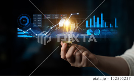Human Hand Holding Light Bulb Against Digital Graphs and Data Visualizations Representing Innovation and Technology in Business Environment Scalp 132895237