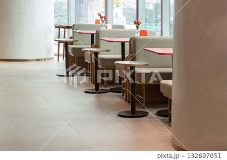a row of tables and booth-style seating in a clean and modern interior of a restaurant. a row of tables and booth-style seating in a clean and modern interior of a restaurant. 132897051