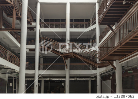 the interior of the Napa Building at Wongwian Yai. The building's design features a contemporary architectural style with a complex arrangement of crisscrossing steel staircases and railings 132897062