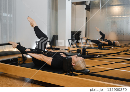 Pilates session in a modern studio with a focus on core strength and flexibility during a morning class Pilates session in a modern studio with a focus on core strength and flexibility during a morning class 132900270