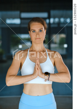 Woman practicing yoga indoors with hands in prayer position in a serene environment Woman practicing yoga indoors with hands in prayer position in a serene environment 132900320