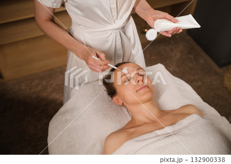 Woman receives a facial treatment in a serene spa environment, enjoying relaxation and skincare therapy for rejuvenation and self-care 132900338