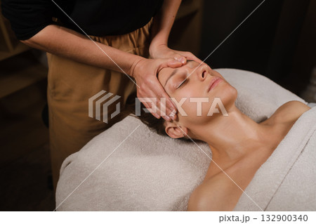 Relaxing massage therapy session in a calm spa setting with a focused therapist and a serene client enjoying the treatment 132900340