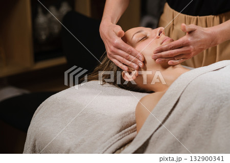 Relaxing facial massage at a spa with a calm atmosphere and soothing lighting, promoting wellness and rejuvenation in a tranquil setting 132900341