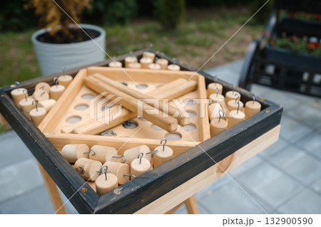 Wooden tabletop game with pieces ready for play in a sunny backyard setting during a summer afternoon gathering 132900590