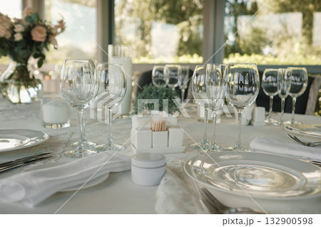 Elegant dining setup with glassware and floral centerpiece at a scenic restaurant during daytime Elegant dining setup with glassware and floral centerpiece at a scenic restaurant during daytime 132900598