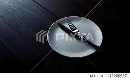 暗いテーブルに白い皿とナイフとフォーク 132900627