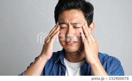 辛そうに手で頭を押さえている若い男性 132900678