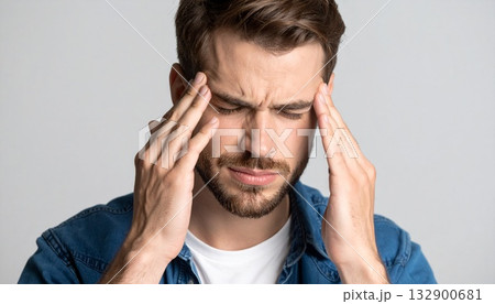 辛そうに手で頭を押さえている若い男性 132900681