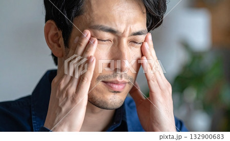 辛そうに手で頭を押さえている若い男性 132900683