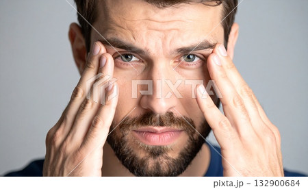 辛そうに手で頭を押さえている若い男性 132900684