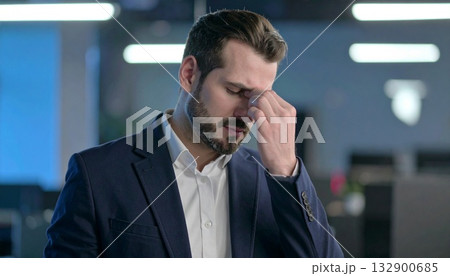 辛そうに手で頭を押さえている若い男性 132900685