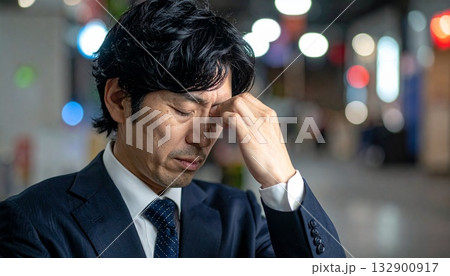 辛そうな表情で手で頭を押さえている中年男性 辛そうな表情で手で頭を押さえている中年男性 132900917