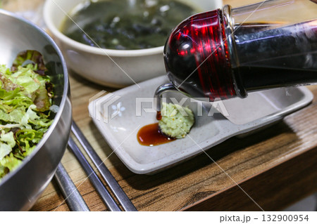 Pour Korean soy sauce into a bowl with wasabi 132900954