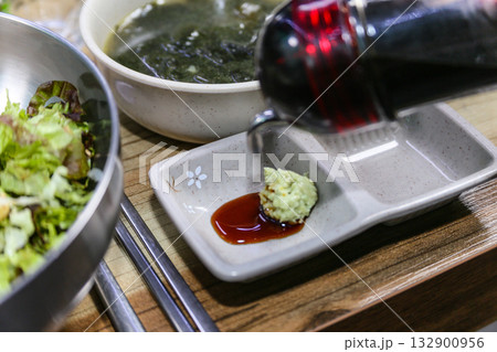 Pour Korean soy sauce into a bowl with wasabi 132900956