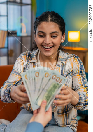 Sudden happiness Indian woman joyfully celebrating receiving plenty cash dollar showing victory sign 132901782
