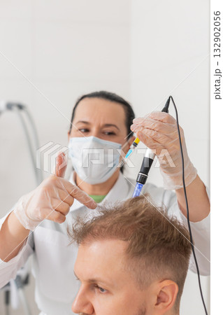 Trichologist doing man improve hair growth procedure, dermapen microneedling, vitamin injections 132902056