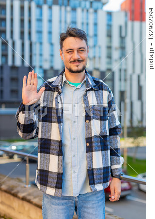 Cheerful mature man tourist smiling at camera, waving hands gesturing hello standing on city street 132902094