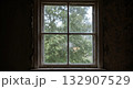 Cracked window with rain in abandoned wooden house during storm with peeling wallpaper and gray light 132907529