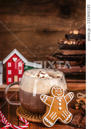 Cup of hot chocolate with whipped cream and gingerbread cookie on wooden table, cozy Christmas composition with chocolate pieces, candy canes and festive background, winter holiday mood Cup of hot chocolate with whipped cream and gingerbread cookie on wooden table, cozy Christmas composition with chocolate pieces, candy canes and festive background, winter holiday mood 132908185