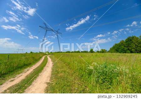 A Tranquil Countryside Path Dancing Under a Blue Sky and Power Lines Stretching Across 132909245
