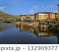Colorful lakeside town Brightly painted buildings reflecting on a calm lake surrounded by green hills, capturing vibrant urban beauty amid nature. 132909377