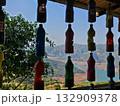 Hanging bottle art Row of colorful recycled plastic bottles hanging as decor with stunning valley and lake view in the background, representing creativity and sustainability. 132909378