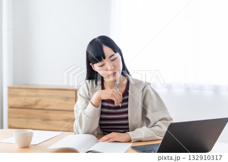 リモート授業を受けてノートをとっている若い女性 132910317